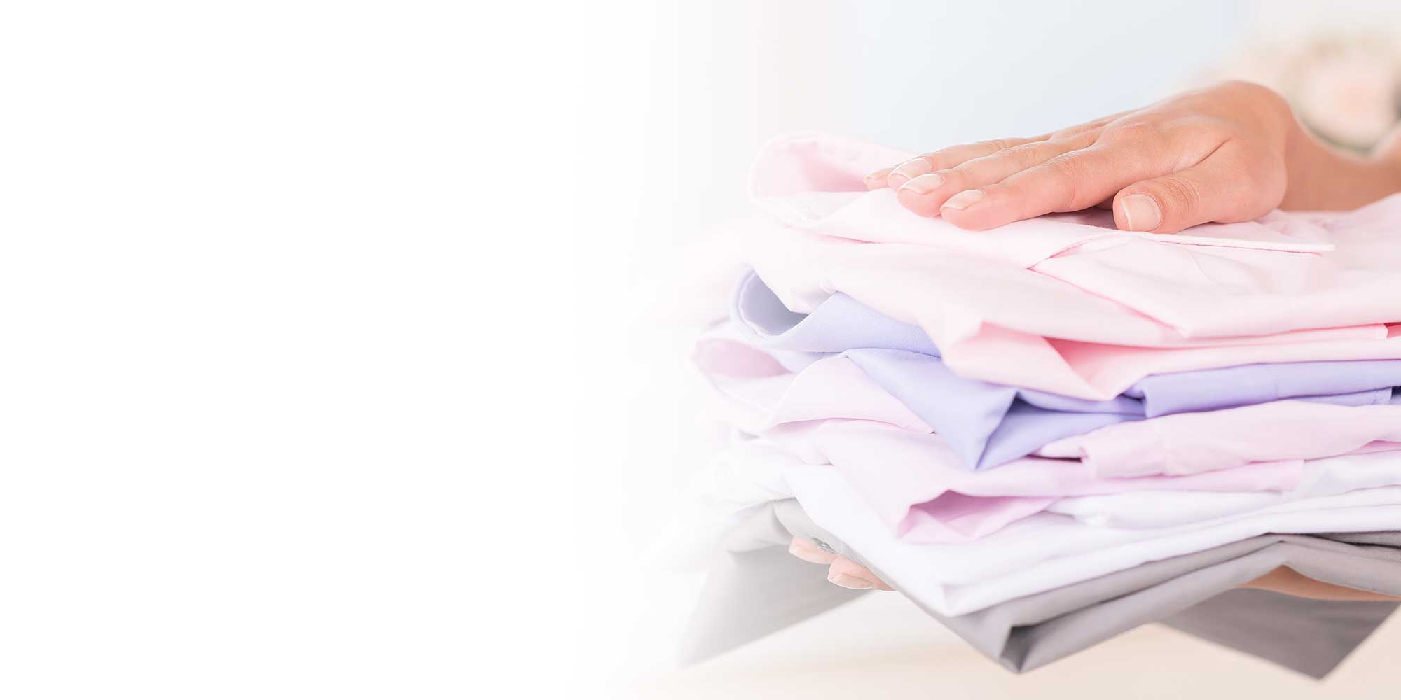 A woman holding freshly cleaned pile of washing, ironed and folded